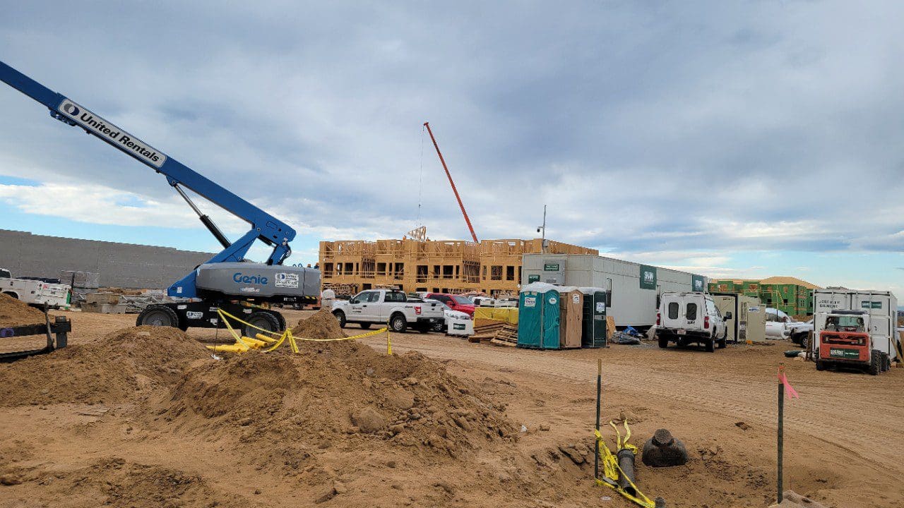 A construction site with trucks and cranes in the background.